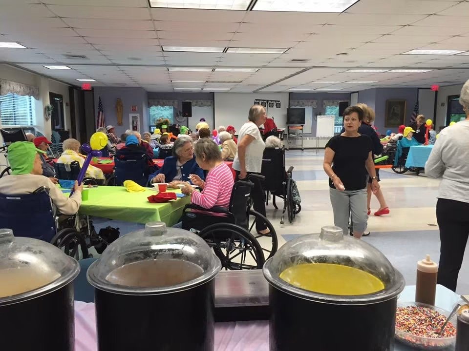 Guests seated at an indoor community-hall gathering with Cold Stone catering tubs in the foreground