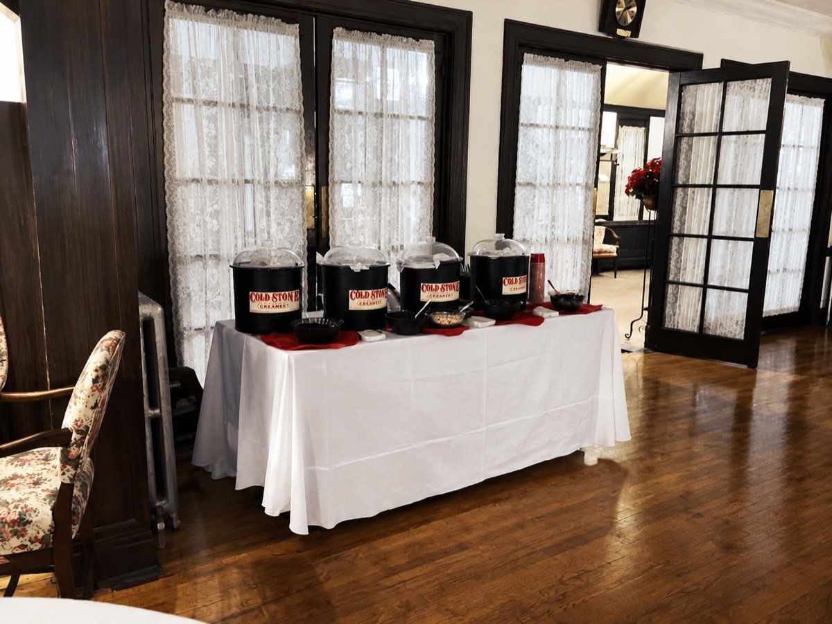 Cold Stone Creamery sundae bar set up with branded catering tubs at an indoor venue